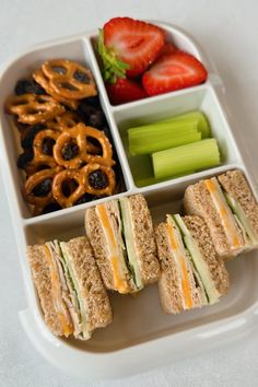 a lunch tray with sandwiches, pretzels and fruit