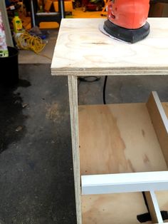 an electric sander sitting on top of a wooden table next to plywood boards