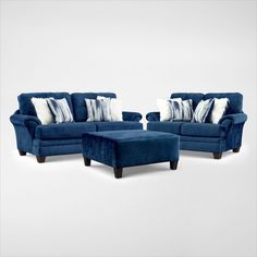 two blue couches and a footstool with pillows