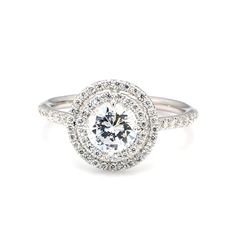 a white gold ring with diamonds on the sides and an oval halo setting in the center