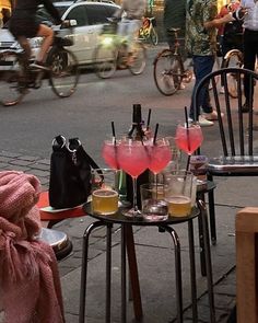 two tables with drinks on them sitting next to each other in the middle of a street