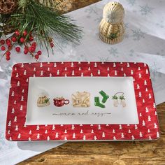 a red and white tray with christmas decorations on it next to a pine cone candle holder