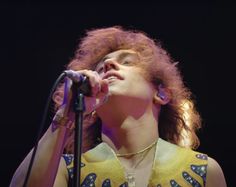 a woman with red hair singing into a microphone