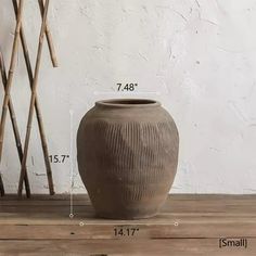 a large brown vase sitting on top of a wooden table next to a planter