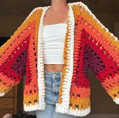 a woman is wearing a crocheted jacket and jeans