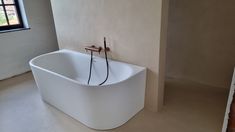 a large white bath tub sitting in the corner of a room next to a window