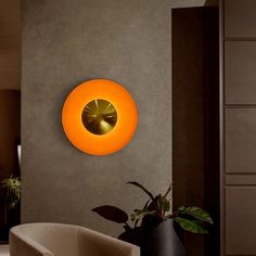 a living room with a round light on the wall and a chair in front of it