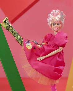 a barbie doll in a pink dress and green tights with her legs spread out