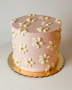 a pink cake with white and gold flowers on it