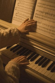 two hands are playing the piano with sheet music on it's back and sides