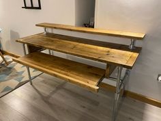 a wooden desk with metal legs and two shelves on each side, against a white wall