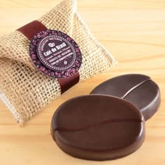 two pieces of chocolate sitting on top of a wooden table next to a brown bag