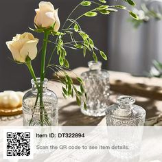 three glass vases with flowers in them on a wooden table next to a qr code