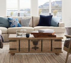 a living room with a couch, coffee table and chairs in front of large windows