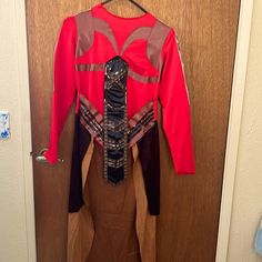 a red shirt hanging on a door with an attached neck tie and belt around it