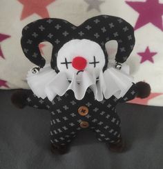 a black and white stuffed animal with red nose, eyes and mouth is standing in front of a star patterned background