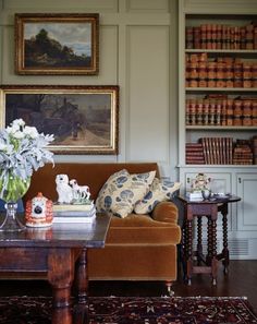 a living room filled with furniture and bookshelves covered in paintings on the walls