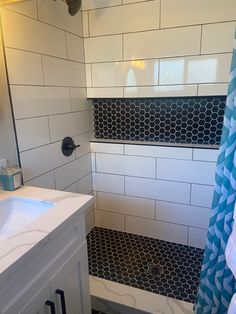 a white bathroom with black and white tile on the shower wall, toilet and sink