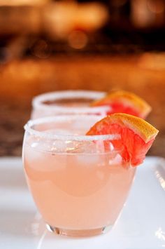 three glasses filled with pink lemonade and garnished with grapefruits