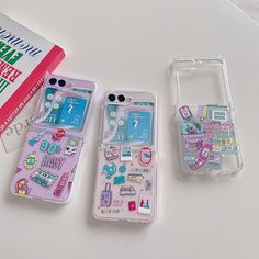 two cell phones sitting next to each other on top of a white table with stickers