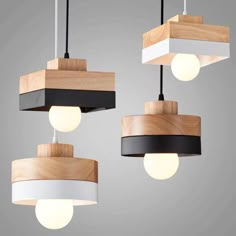 three wooden lights hanging from the ceiling with white, black and grey shades on them