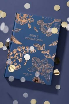 a blue book with gold foiling and confetti on the cover, surrounded by small white dots