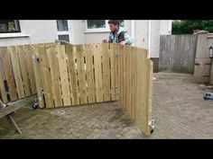 a man is standing behind a wooden fence