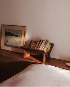 a wooden shelf with books on it next to a bed