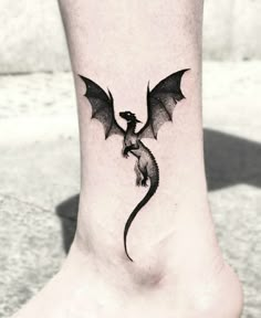 a small black dragon tattoo on the ankle