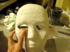 a person is making a mask out of white clay on a table with other items