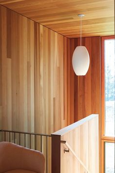 a room with wood paneling and a light fixture hanging from the ceiling next to a chair