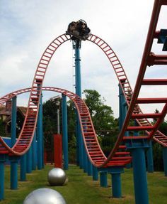 an amusement park with roller coasters and balls in the grass next to each other