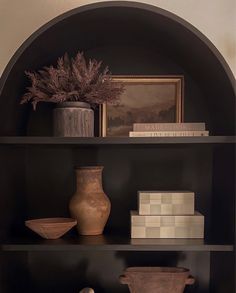 a shelf with vases, books and other items on it in a living room