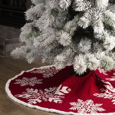 a white christmas tree with red and white snowflakes on it's base