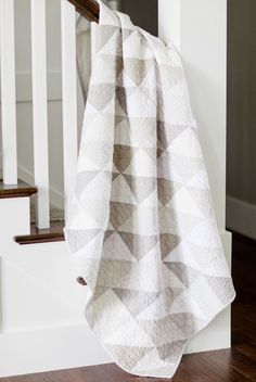 a white and brown blanket sitting on top of a wooden floor next to a stair case