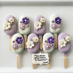 purple and white cake pops with daisies on them are arranged in a square frame