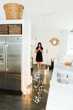 a woman standing in front of a refrigerator freezer next to a kitchen with lots of confetti on the floor