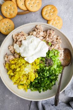 a white bowl filled with food next to crackers on top of a gray table