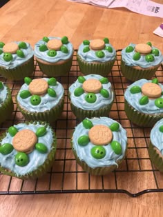 cupcakes decorated with green and white icing on a cooling rack