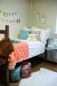 a bed with many pillows and blankets on it, along with pictures hanging from the wall