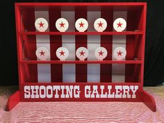 a display case with red and white striped paper on it that says shooting gallery in the center