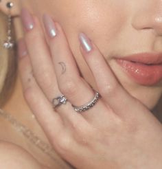 a close up of a person with rings on their fingers and hand near her face