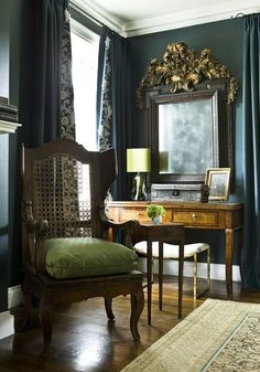 an antique desk and chair in front of a mirror with curtains on the windowsill