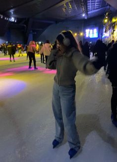 a woman is standing in the middle of an ice skating rink with headphones on