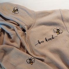 "\"Bee kind\" slogan embroidered hoodie. Cute Bee design on left chest, right sleeve and on the edge of the hood. Delivered to you in an organic cotton stuff bag decorated with a cute embroidered Bee. Lovely soft cosy brushed back fleece, drop shoulder,unlined hood,front pocket,ribbed cuff and hem. SIZE GUIDE: sizes are approximate please check  photos for measurements TO FIT CHEST.  31/34.    XS                             34/37.     S                             38/41.     M  length 27\" 70cm                             42/45.     L length 29\" 74cm                             46/49.    XL length 29\" 74cm COLOUR: SAND WITH BLACK AND GOLD EMBROIDERY" Embroidery Designs For Hoodie, Hoodie Embroidery Ideas, Bee Sweatshirt, Stuff Bag, Embroidered Bee, Hoodie Cute, Trendy Hoodies, Embroidery Hoodie, Bee Kind