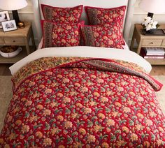 a bed with red bedspread and matching pillows