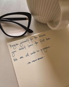 a note that is on top of a table next to a coffee cup and eyeglasses