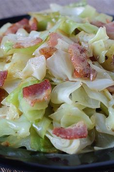 a black plate topped with cabbage and bacon