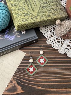 a pair of earrings sitting on top of a wooden table next to a pile of books