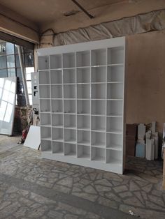 a white bookcase sitting in the middle of a room next to a wall filled with boxes